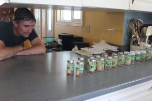 Paul Brooks of Brook Line in Dresden examines a series of well water samples he collected prior to his water turning cloudy in July 2017.